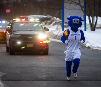 Victor E. Bull escorting the torch outside of Ellicott Complex. Photo: Meredith Forrest Kulwicki