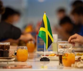 Jamaican flag on the table next to commemorative glasses and international food during the event. Photo: Meredith Forrest Kulwicki