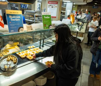 Student retrieving a couple boats of poutine during the event. It's a station featuring dishes from Canada, so it's also placed next to mushroom tourtière. Photo: Meredith Forrest Kulwicki